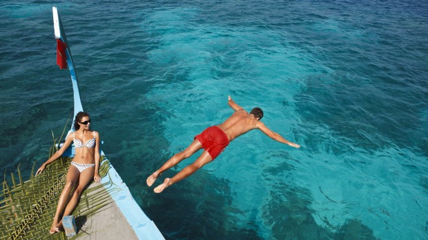 A tourist takes a dive from a dhoni boat.