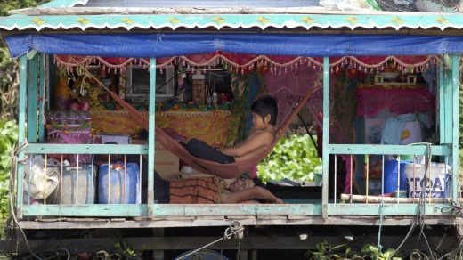 Families escape from the tropical heat to the cool verandah of this floating house on Tonle Sap Lake.