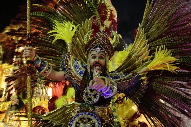 A performer from Estacio de Sa samba school points directly at the camera as he parades on a float during the Carnival ...