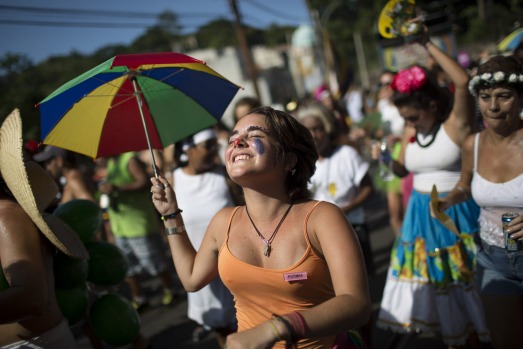 A reveler holds up a colored umbrella as she dances at the "Carmelitas" block party during Carnival celebrations in Rio ...