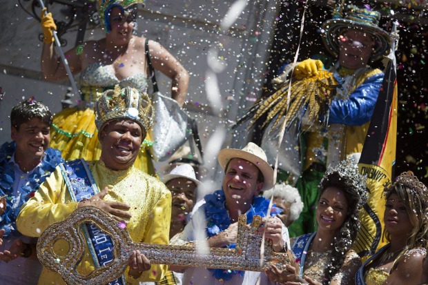 The 2016 Carnival King Momo, Wilson Dias da Costa Neto, left, holds the key of the city with Rio de Janeiro's Mayor ...