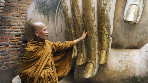 A monk visits the giant Buddha statue at Wat Si Chum in Sukothai Historical Park.