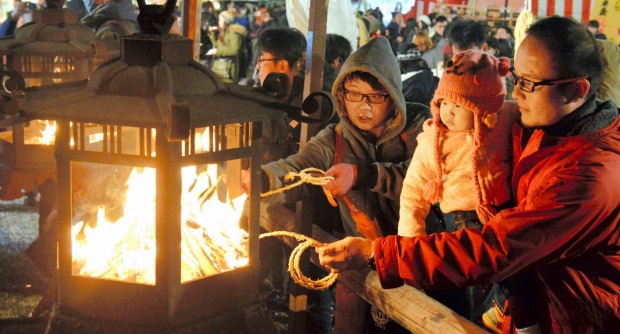 KYOTO: Visitors light to ropes during the Okera-sai in pray for good health and happiness in the New Year at Yasaka ...