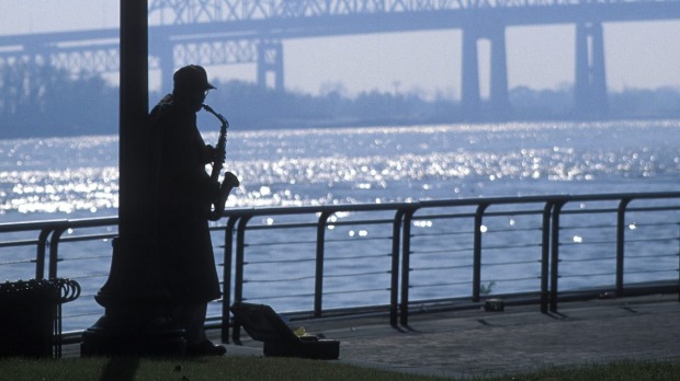 A busker playing by Mississippi river in New Orleans.