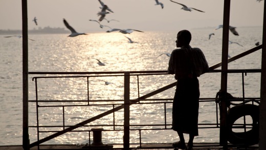 A monk feed seagulls from a pier in Mawlamyine.