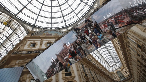 Tourists are reflected in the mirrors of an installation on Milan's history at the restored Galleria Vittorio Emanuele ...