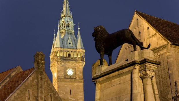 A 12th-century bronze lion at Braunschweig castle square, with the town hall in the background.