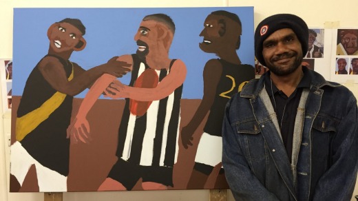 Vincent Namatjira with a painting (by him) of the Indulkana Tigers, his local footie team.