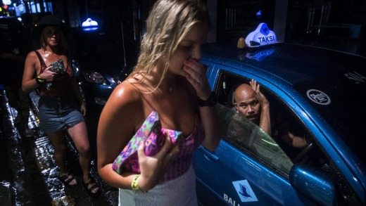 A taxi driver watches two schoolies walk past in Bali.