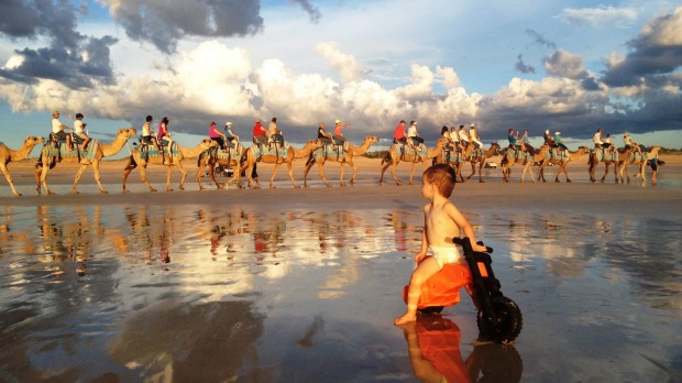 A child watches camels taking tourists along Cable Beach, Broome.