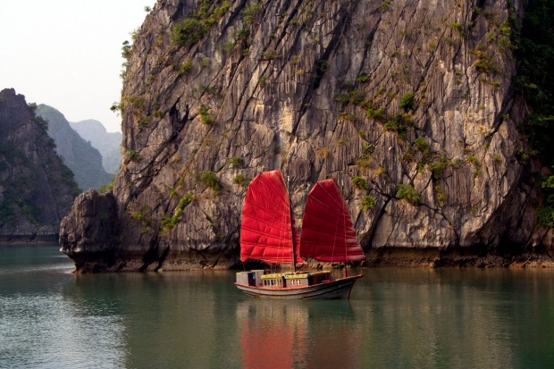 A junk sails past limestone karst mountains in Ha Long Bay.