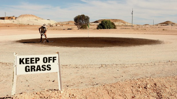 A local rakes out the green at the Coober Pedy Golf Course.