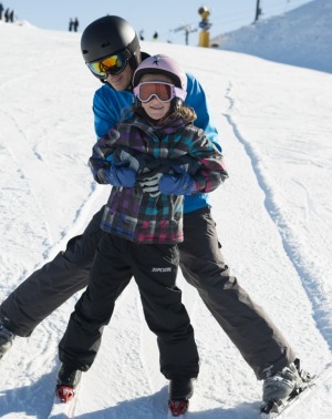 Dad helping daughter on the beginner slopes.