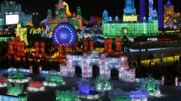 People visit ice sculptures illuminated by coloured lights during the opening day of the Harbin International Ice and ...