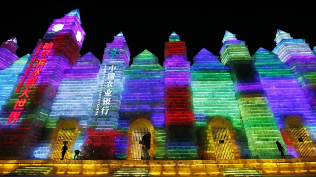 People visit ice sculptures illuminated by coloured lights during the opening day of the Harbin International Ice and ...