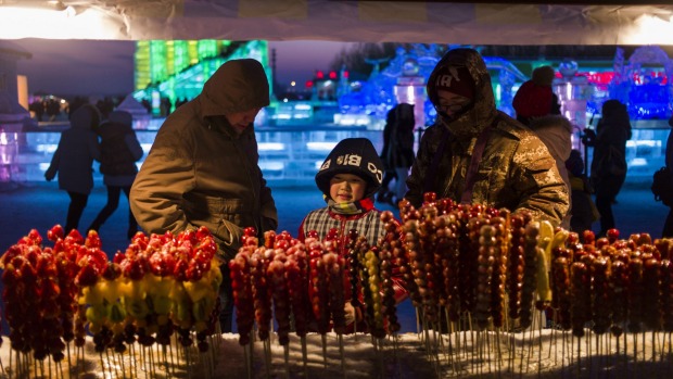 A child eyes fruit candy sticks during the Harbin International Ice and Snow Festival in Harbin, northeast China's ...