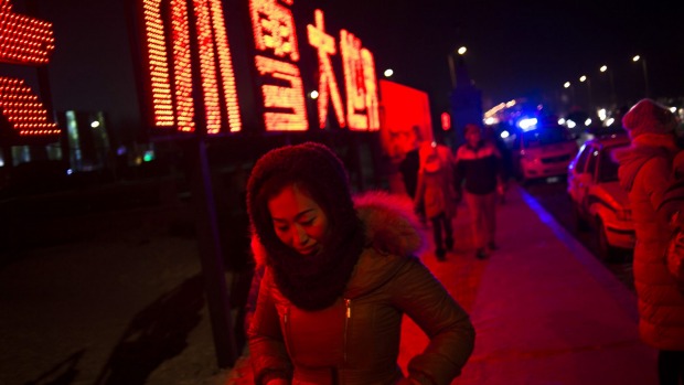 A woman walks under lit characters during the Harbin International Ice and Snow Festival in Harbin, northeast China's ...