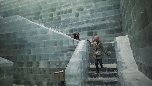 Visitors walk on an ice castle at the China Ice and Snow World during the Harbin International Ice and Snow Festival in ...