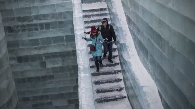 Visitors walk on an ice castle at the China Ice and Snow World during the Harbin International Ice and Snow Festival in ...