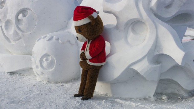 A man clad in a teddy bear suit leans on a snow sculpture during the Harbin International Ice and Snow Festival in ...