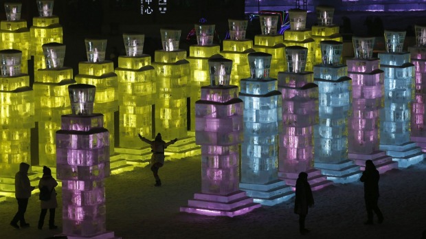 Visitors get a peak at ice sculptures are illuminated by coloured lights on the eve of the official opening of the festival.