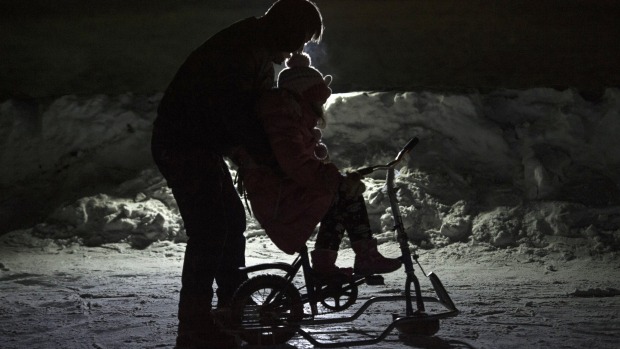 A father helps his son to ride a cycle over ice during the Harbin International Ice and Snow Festival in Harbin, ...
