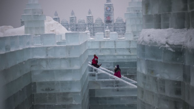 Visitors walk through an ice castle on the eve of the opening of the Harbin International Ice and Snow Festival in ...