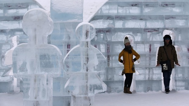 A couple poses for photos with an ice sculpture on the eve of the opening ceremony of the Harbin International Ice and ...