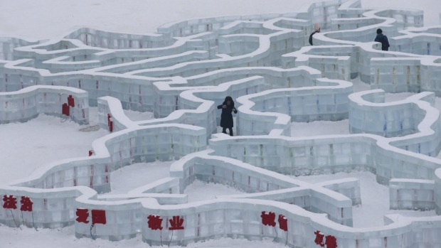 A visitor makes her way in a maze made from ice bricks ahead of the opening day of the Harbin International Ice and Snow ...