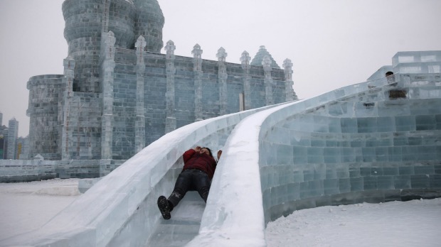 A woman rides a slide on an ice sculpture on the eve of the opening ceremony of the Harbin International Ice and Snow ...