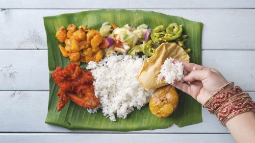 Indian woman eating banana leaf rice.