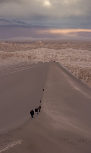 People hiking up a sand dune in Valle de la Luna.