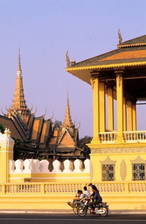 On the move ... a woman works in a rice field; the Royal Palace in Phnom Penh.