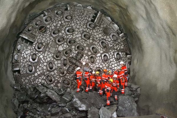 THE LONGEST RAILWAY TUNNEL IN THE WORLD:  Miners stand in front of the "gaby" drill digging the world's longest tunnel.