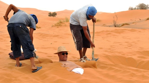 Sun and sand of a different kind: A tourist takes a sand bath in the dunes of the Merzouga desert in southeastern Morocco.