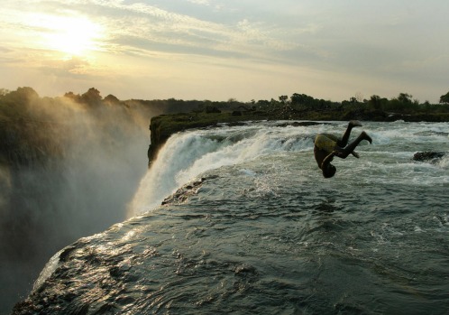 A Zambian man somersaults into a pool at the edge of the 110-metre high main falls of the Victoria Falls on the Zambezi ...