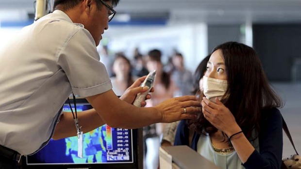 A quarantine officer checks body temperature of a passenger against possible infections of Ebola virus at the Incheon ...