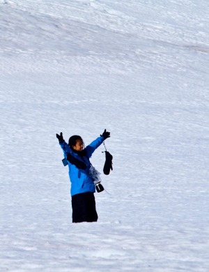A tourist on a snowy mountainside celebrates being in Antarctica.