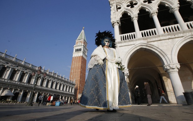 A masked woman walks in St. Mark's square during the Venice Carnival, in Venice, Italy. The Venice carnival in the ...