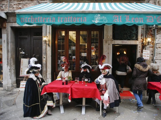 Masked people enjoy a drink in Venice, Italy.
