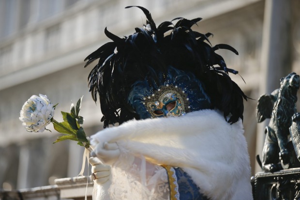 A masked woman poses in St. Mark's square during the Venice Carnival, in Venice, Italy. The Venice carnival in the ...