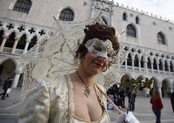 A masked woman walks prior to the Carnival Grand Opening show, in Venice, Italy. The Venice carnival in the historical ...