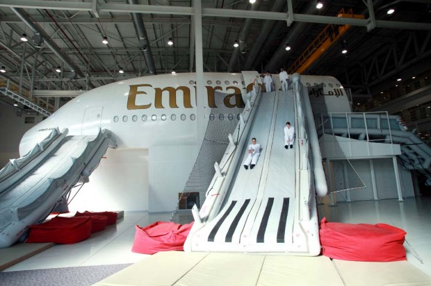 Trainee flight attendants for Emirates practice an emergency exit using escape chutes on an Airbus A380 simulator.