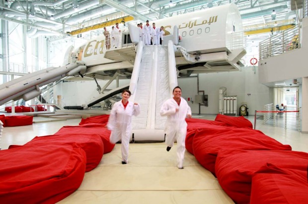 Trainee flight attendants for Emirates practice an emergency exit using escape chutes on an Airbus A380 simulator.