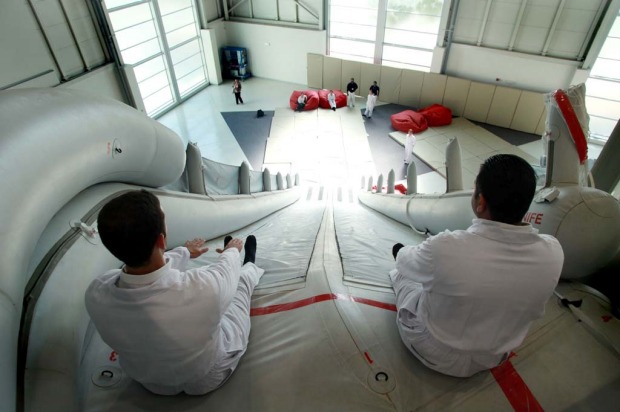 Trainee flight attendants for Emirates practice an emergency exit using escape chutes on an Airbus A380 simulator.