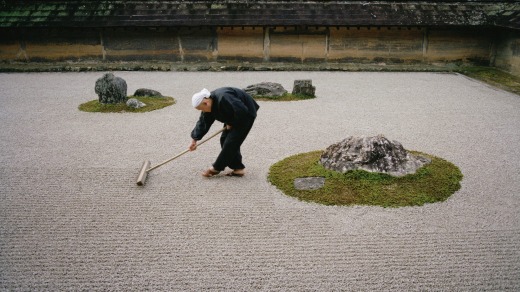 A young monk rakes the famous Japanese rock garden of  Ryoan-ji early in the morning.
