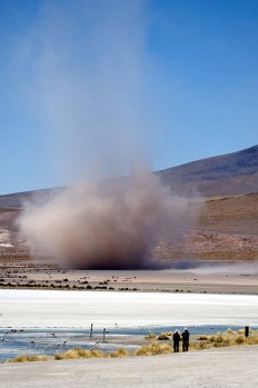 Two men observe a tornado at the Hedionda Lagoon in the Uyuni salt flats, Bolivia.