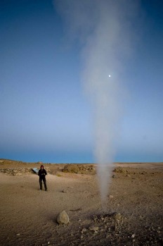 A tourist watches steam being let off by a fumarole at the Uyuni salt flats, Bolivia.