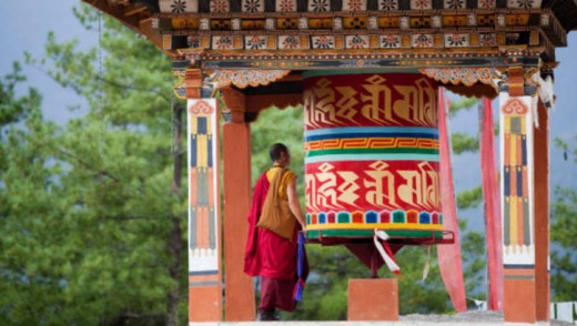 A monk at a temple prayer wheel.