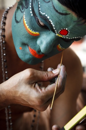 A Kathakali dancer prepares for a performance. The make-up session is one of the attractions of the event.